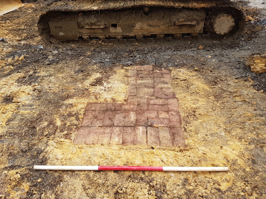 Archaeological brick path preserved under concete building.